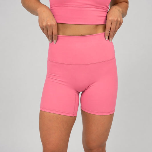 Person wearing Hybryd pink activewear shorts and top on a plain background