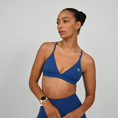 Hybryd athlete wearing a minimal blue sports bra with thin straps.