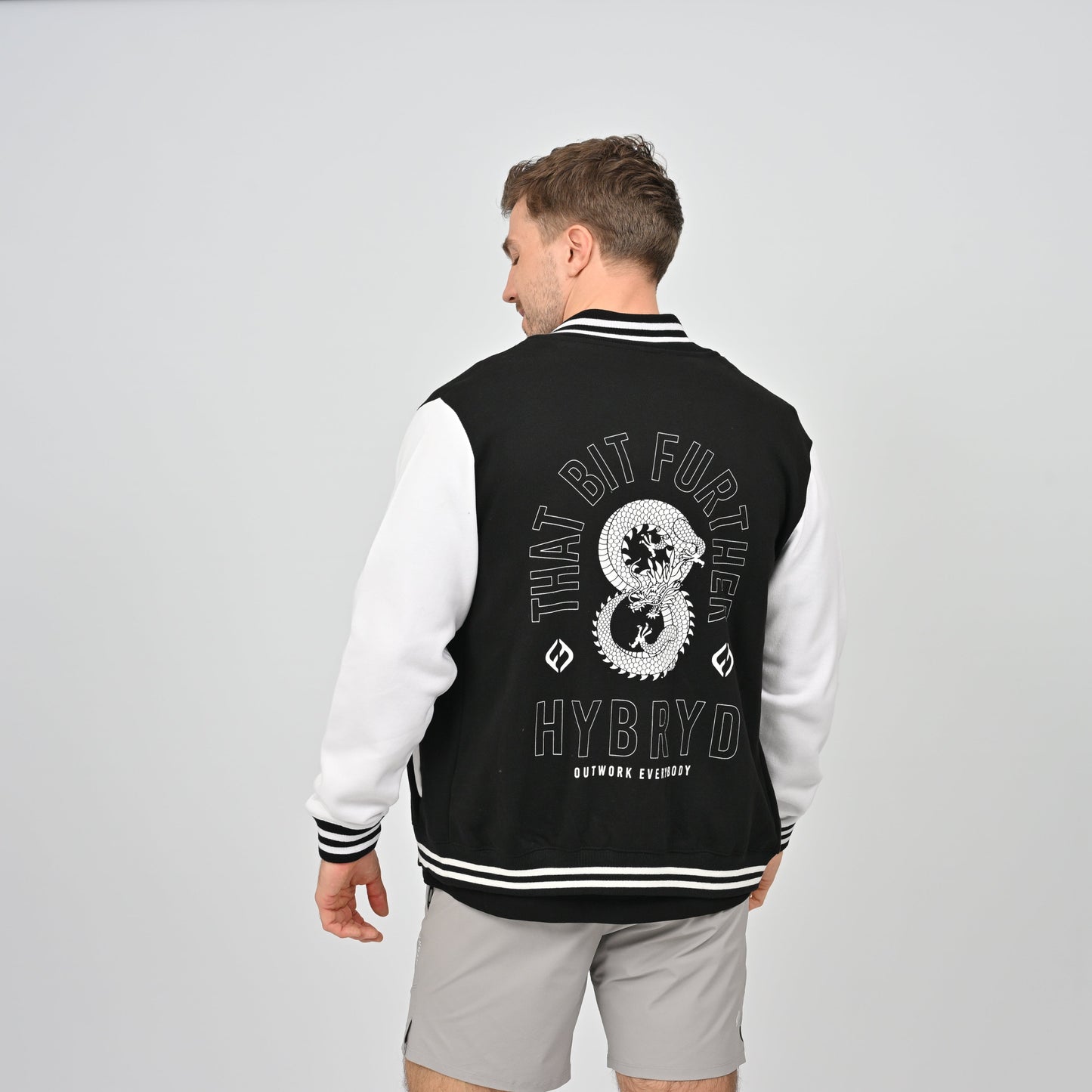 Hybryd athlete in a collegic varsity jacket with dragon print