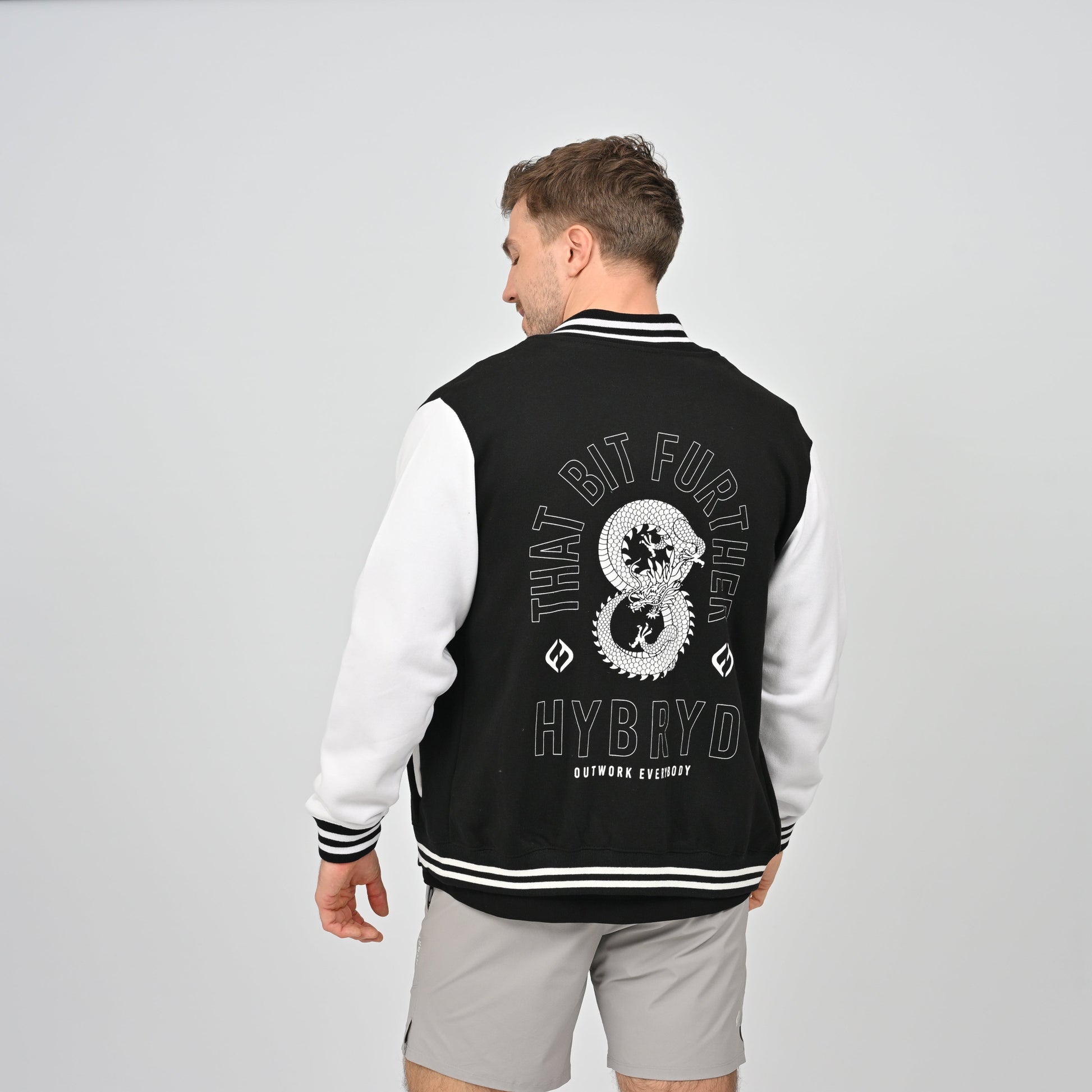 Hybryd athlete in a collegic varsity jacket with dragon print