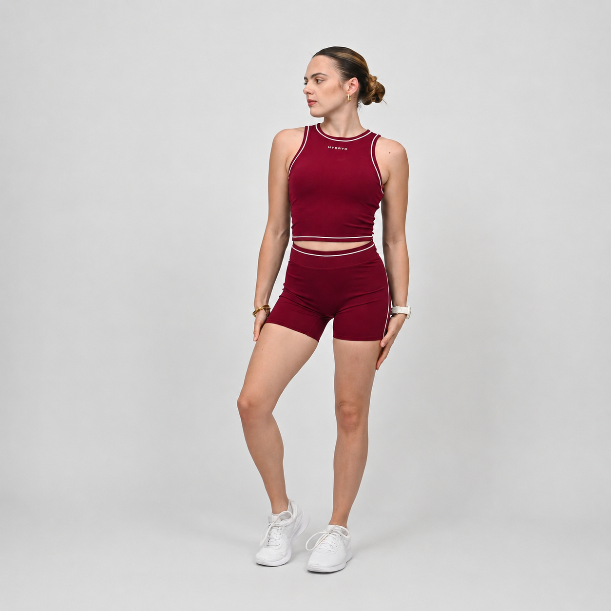 Crossfit athlete wearing a red gym set with a tank and shorts with white piping on a gray background