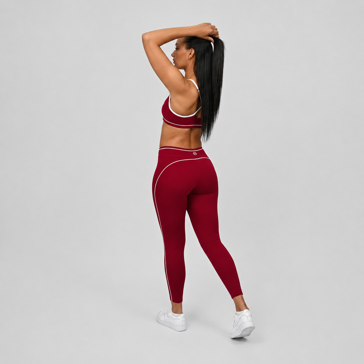 Hybryd yoga athlete wearing a red crossfit gym outfit with white stripes on a gray background