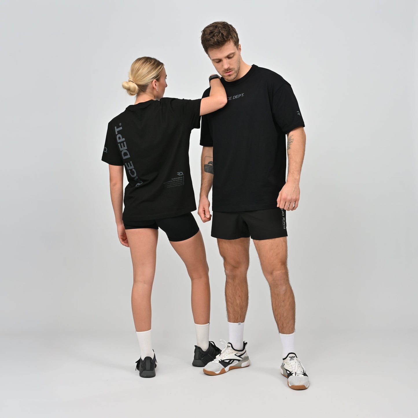 Two people wearing matching black t-shirts and shorts made by Hybryd