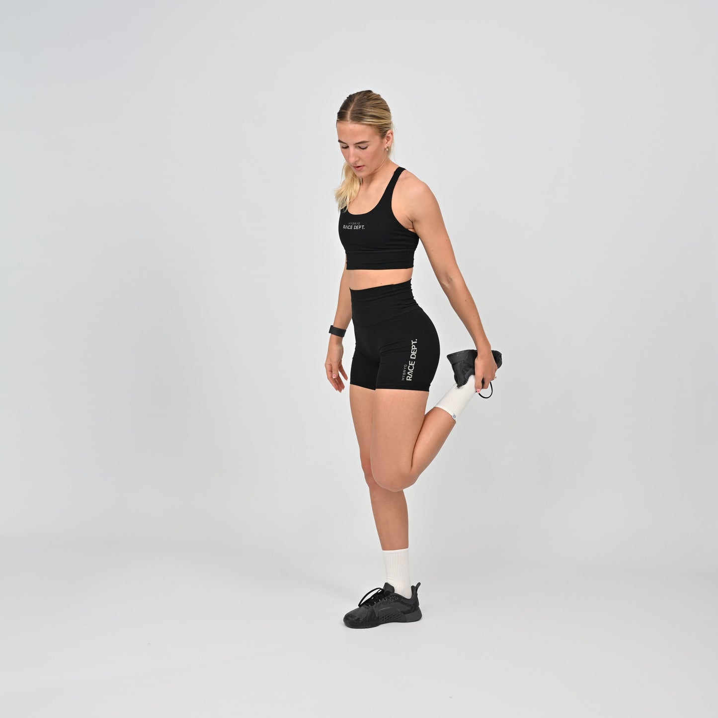 Woman wearing a black athletic outfit with Hybryd branding on a gray background