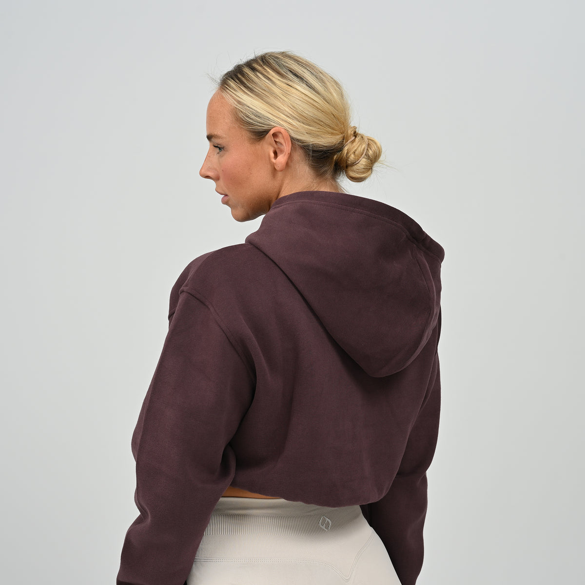Back profile view of model wearing the aubergine Hybryd Barstow cropped sweatshirt hoodie component