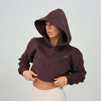 Front view of model wearing the aubergine Hybryd Barstow cropped hoodie with hood up   