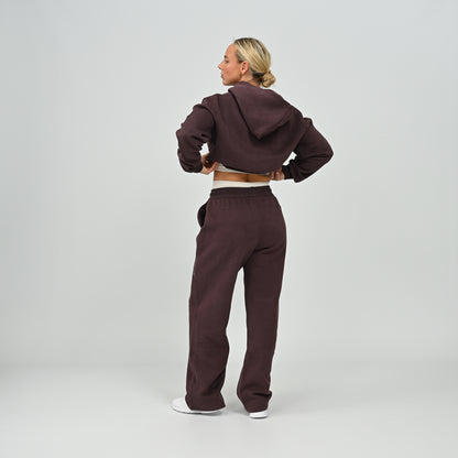Full length back view of model posing in the aubergine Hybryd Barstow cropped hoodie and wide leg joggers set