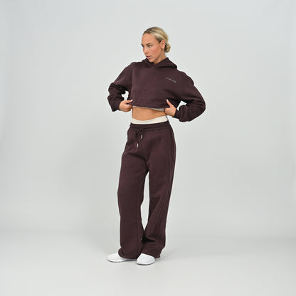 Front side view of model wearing the full aubergine Hybryd Barstow cropped hoodie and wide leg jogger matching set