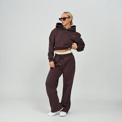 Front view of model wearing the aubergine Hybryd Barstow cropped hoodie and wide leg joggers matching lounge set