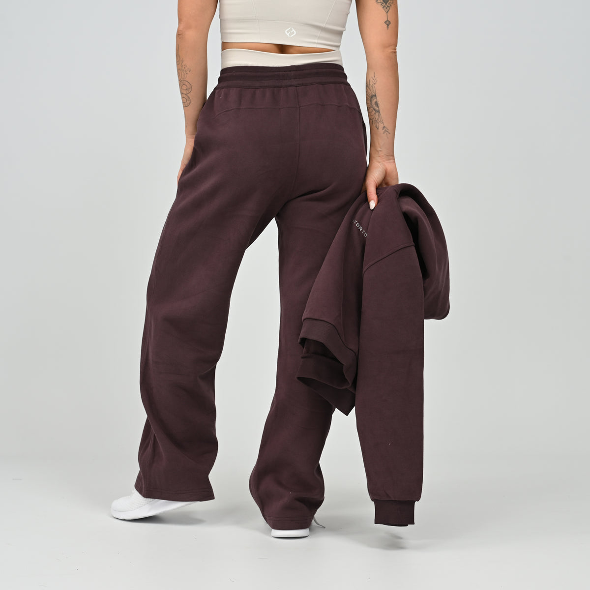 Model holding the aubergine Barstow cropped hoodie while wearing matching wide leg joggers   