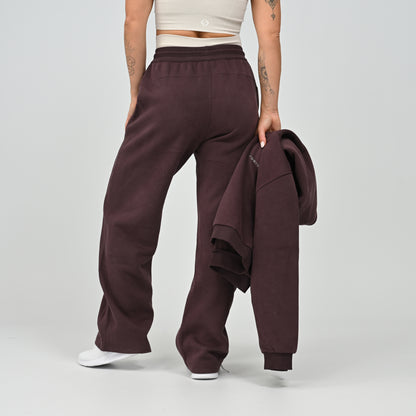 Model holding the aubergine Barstow cropped hoodie while wearing matching wide leg joggers   