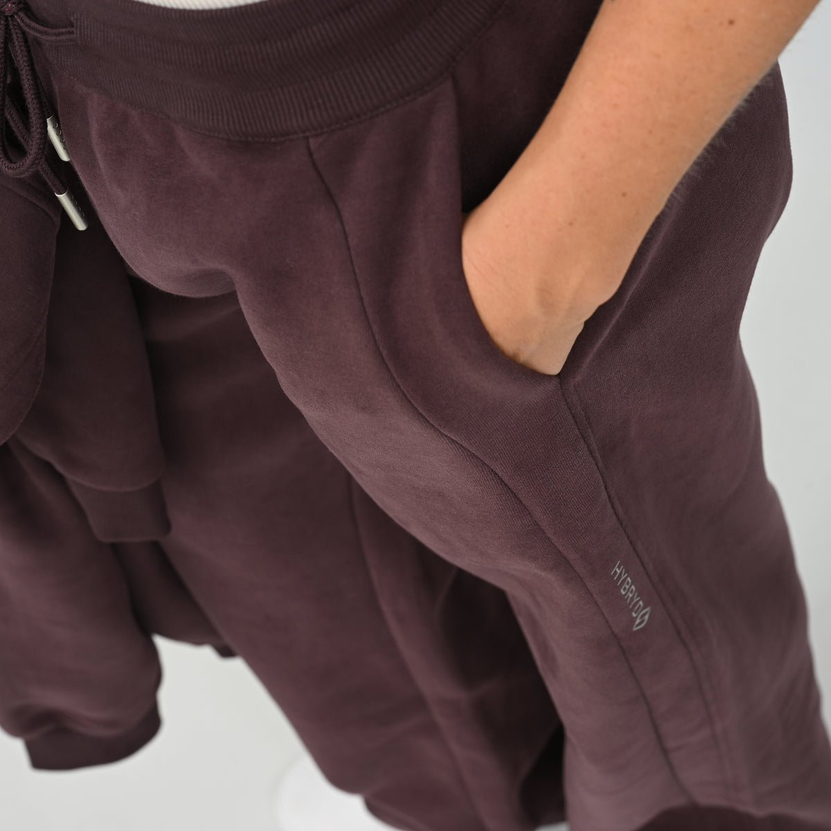 Close-up view of hand in pocket detail on the aubergine Hybryd Barstow wide leg joggers   