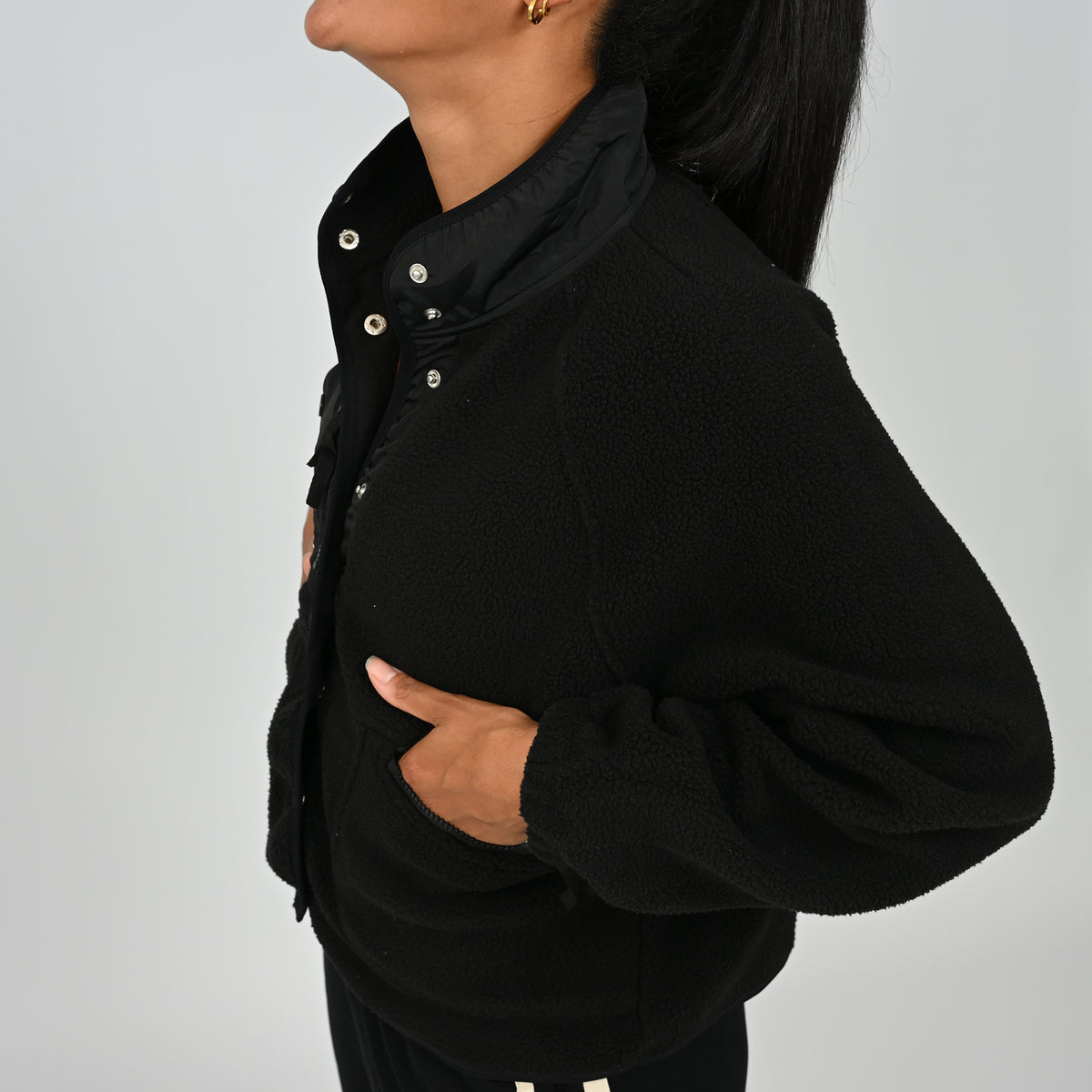 Side profile view showing hand in zipped pocket on women's black Hybryd Huntsville fleece jacket