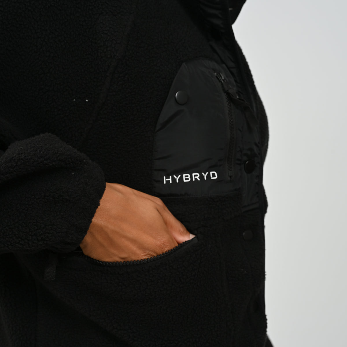 Close-up view of sleeve elasticated cuff and zipped pocket on women's black Hybryd Huntsville fleece