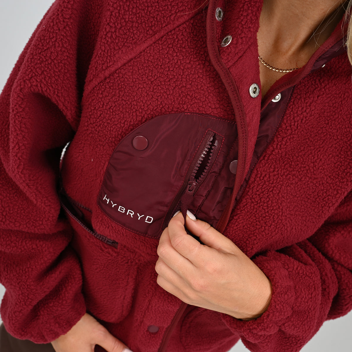 Detail shot of button-up front closure and chest pocket on women's wine Hybryd Huntsville teddy fleece jacket