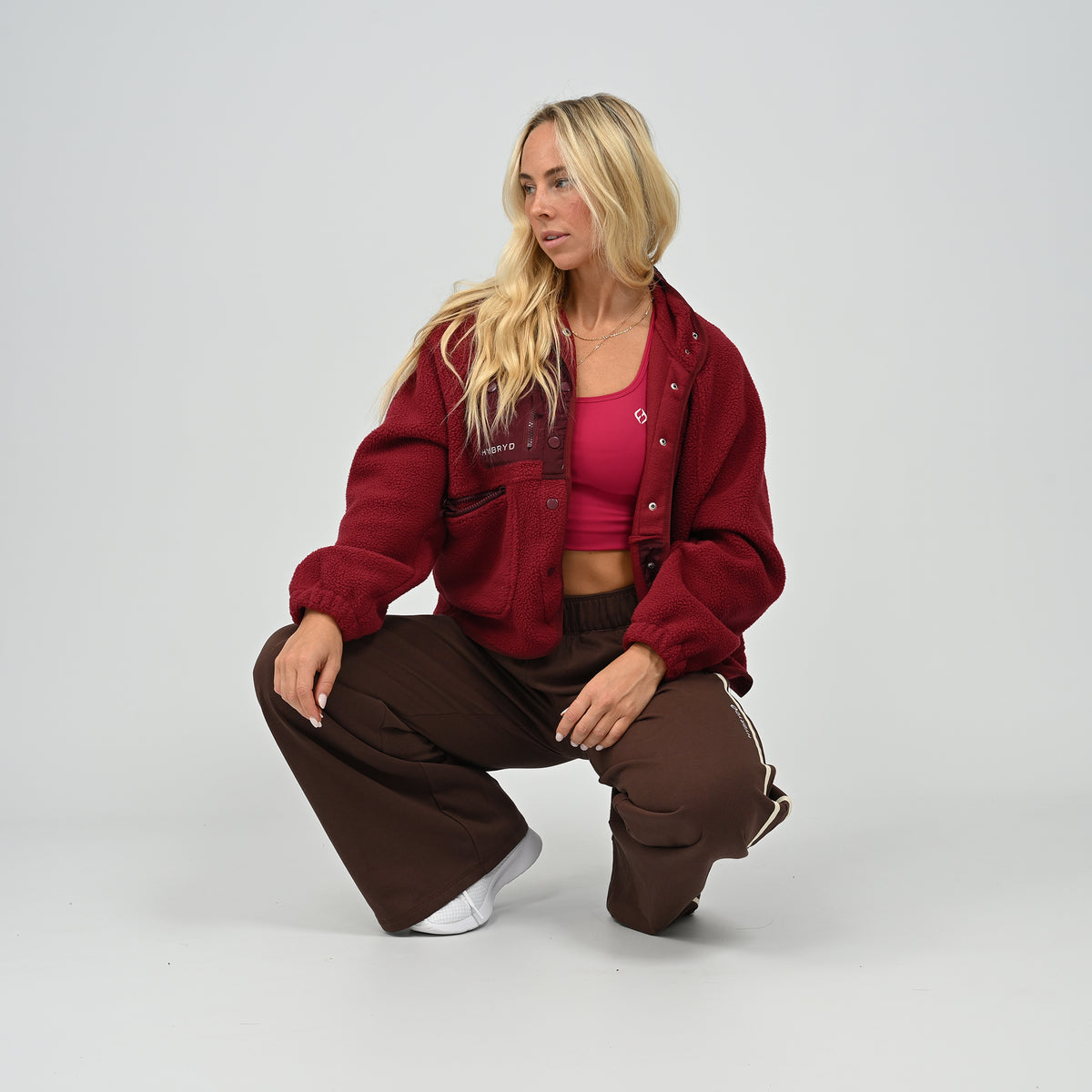 Model wearing buttoned-up women's wine burgundy Hybryd Huntsville cozy teddy bear fleece jacket standing