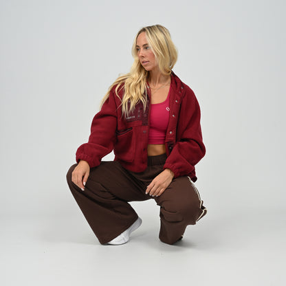 Model wearing buttoned-up women's wine burgundy Hybryd Huntsville cozy teddy bear fleece jacket standing