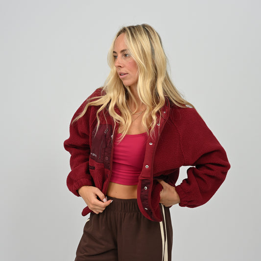 Model wearing open unbuttoned women's wine red Hybryd Huntsville teddy fleece jacket with crop top