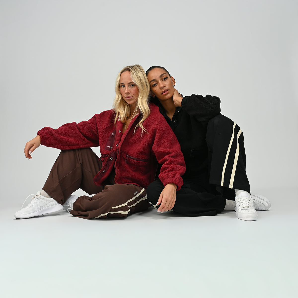 Female model seated on floor wearing women's wine burgundy Hybryd Huntsville cozy teddy fleece jacket