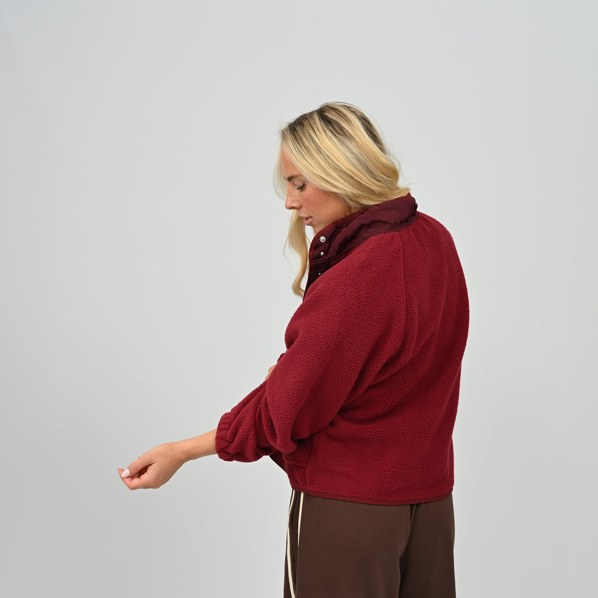 Side profile view of female model wearing women's wine red Hybryd Huntsville teddy fleece jacket with elasticated cuffs