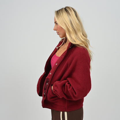 Three-quarter view of female model wearing women's wine burgundy Hybryd Huntsville warm fleece jacket