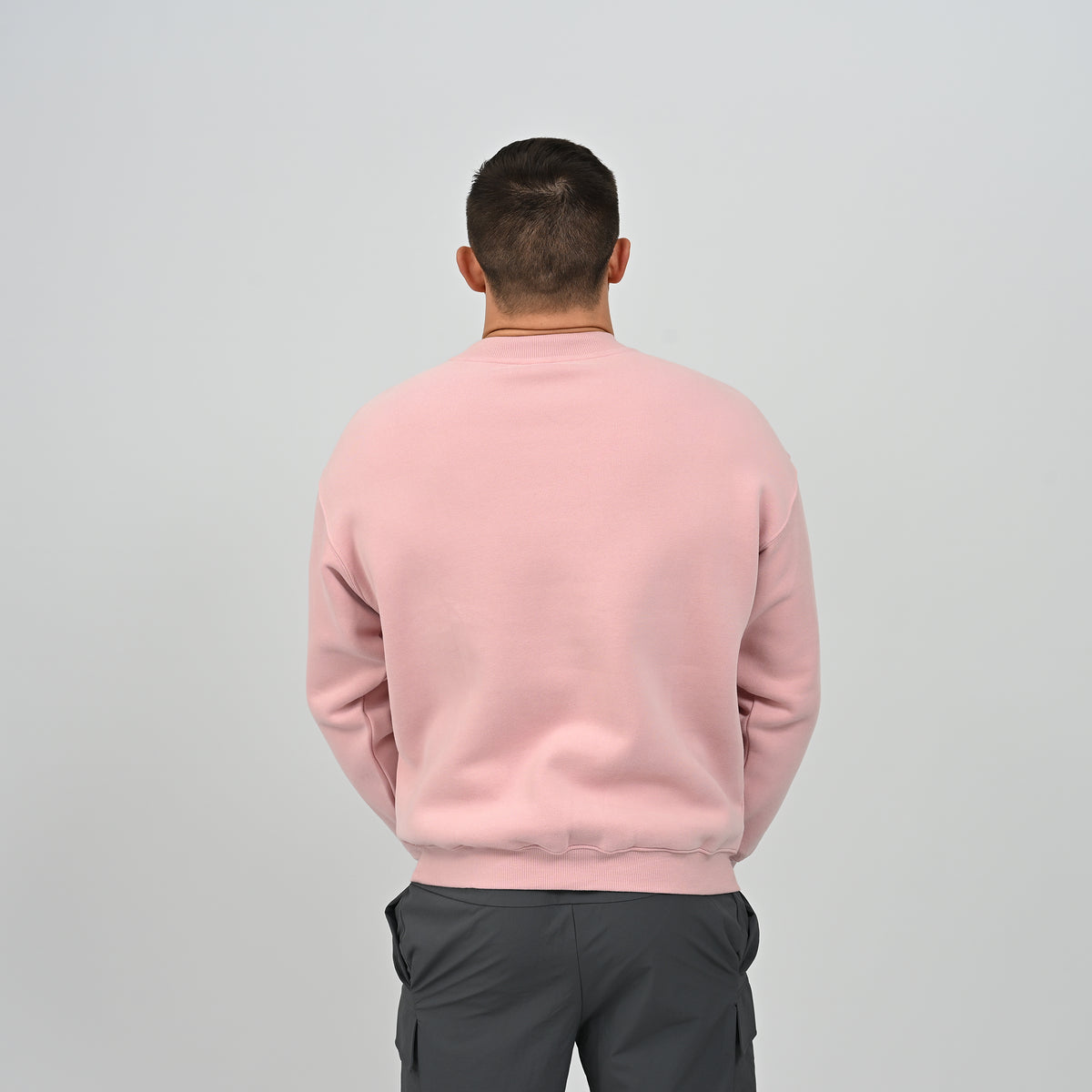 Rear view of model wearing the pink Hybryd Jasper crew neck sweatshirt with ribbed hem.