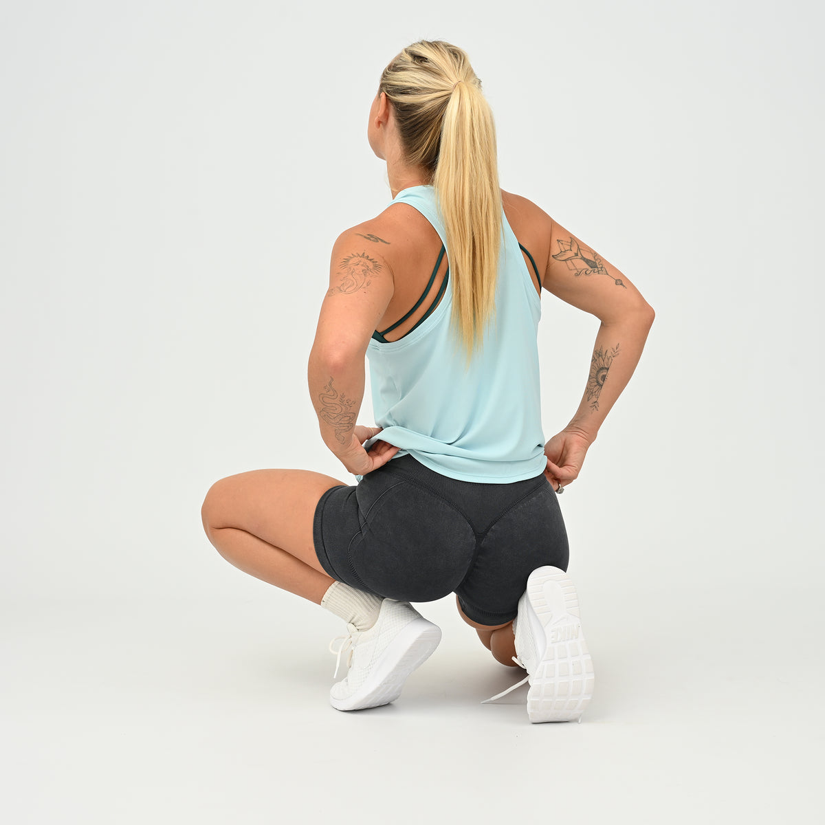 Women’s Luna blue racerback training vest in squat position