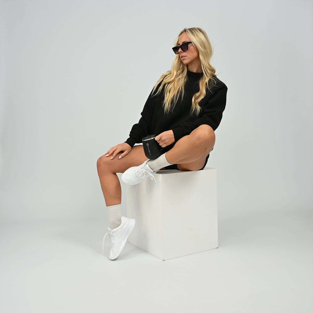 Model sitting wearing the full black Hybryd Scottsdale matching crewneck sweatshirt and shorts set