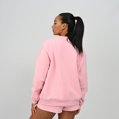 Back view of model wearing the pink Hybryd Scottsdale oversized crewneck sweatshirt and matching shorts set   