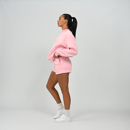 Full body side view of model wearing the pink Hybryd Scottsdale crewneck sweatshirt and matching shorts set
