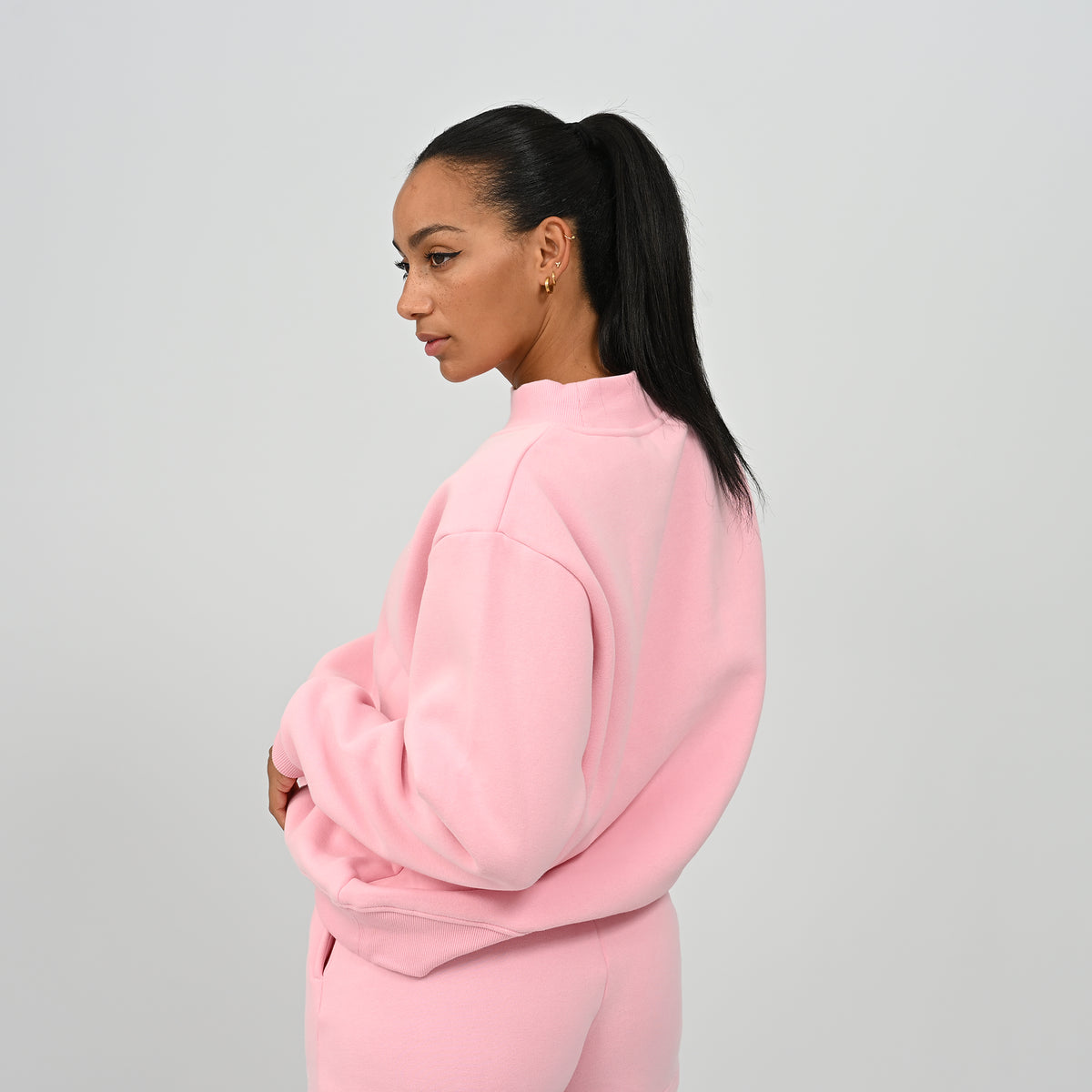 Side profile view of model wearing the pink Hybryd Scottsdale crewneck sweatshirt and matching shorts set