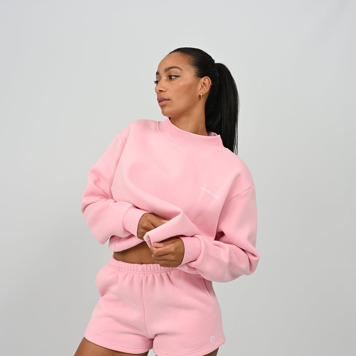 Three-quarter angle of model wearing the pink Hybryd Scottsdale crewneck sweatshirt and matching shorts set