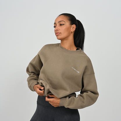 Front angled pose of female model wearing the khaki Hybryd Jasper crew neck jumper showing drop shoulder fit.