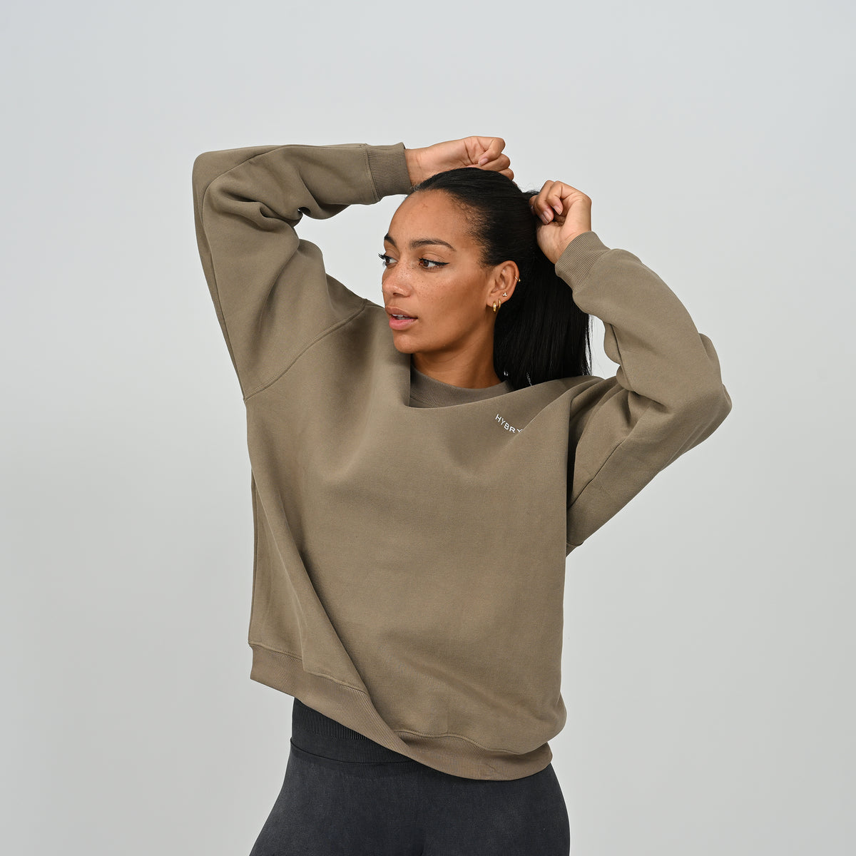 Female model posing with arms raised in the Women's Hybryd Jasper crew neck sweatshirt in khaki.