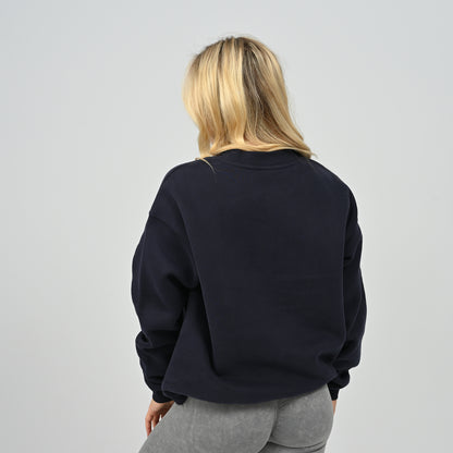 Rear view of female model wearing the Women's Hybryd Jasper fleece crew neck sweatshirt in navy with ribbed hem.