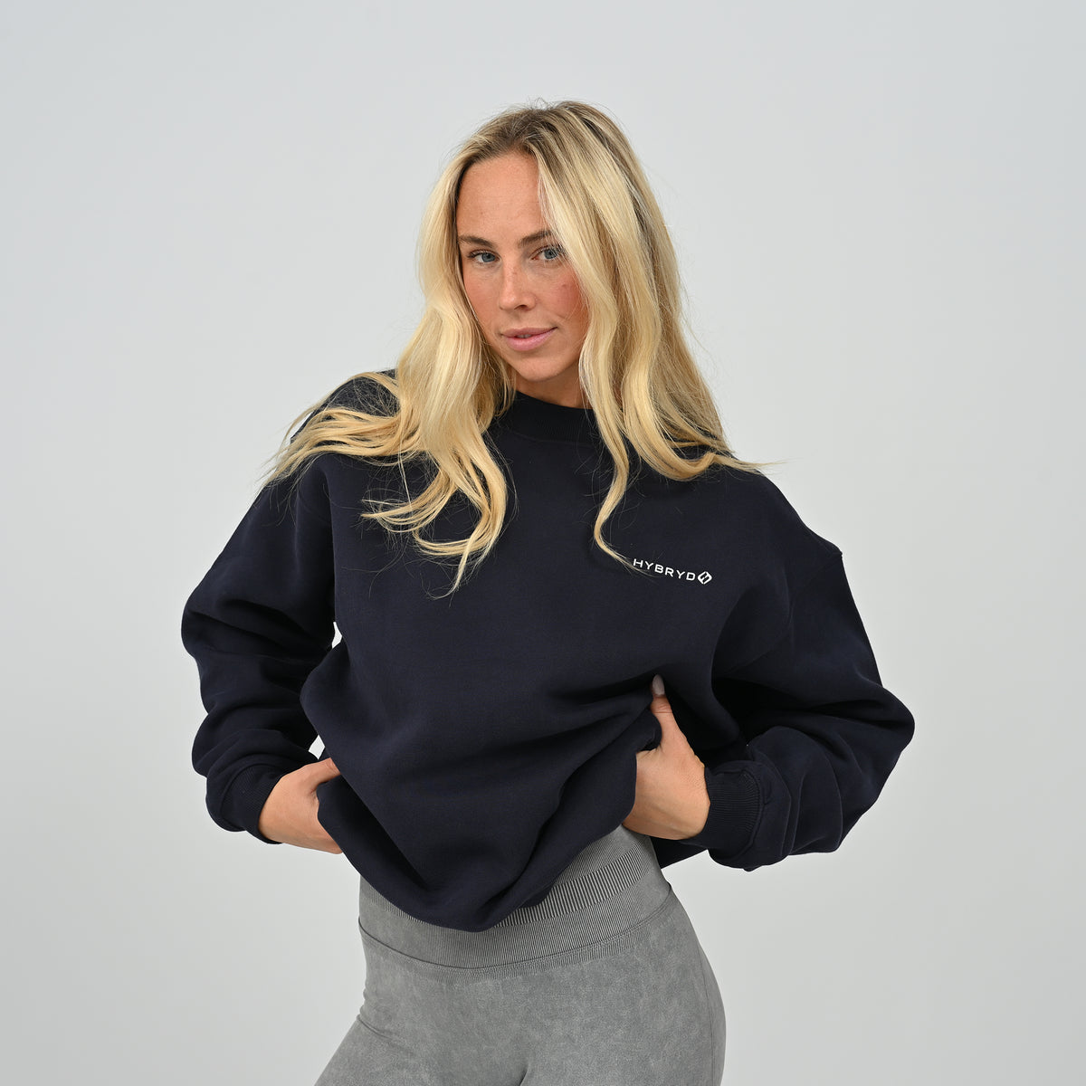 Front view of female model wearing the Hybryd Women's Jasper relaxed fit fleece-lined crew neck sweatshirt in navy blue.