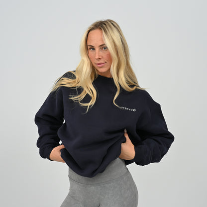 Front view of female model wearing the Hybryd Women's Jasper relaxed fit fleece-lined crew neck sweatshirt in navy blue.