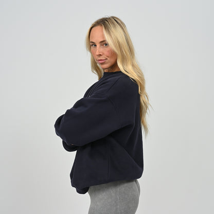 Side angled shot of female model wearing the navy Women's Hybryd Jasper fleece-lined crew neck sweatshirt