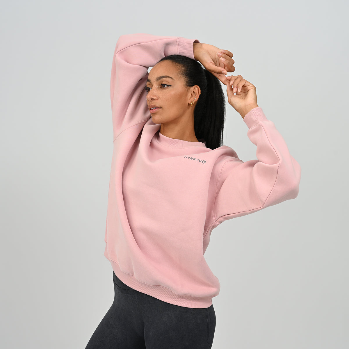 Female model with hands up wearing the pink Hybryd Jasper fleece-lined crew neck sweatshirt.