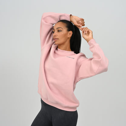 Female model with hands up wearing the pink Hybryd Jasper fleece-lined crew neck sweatshirt.