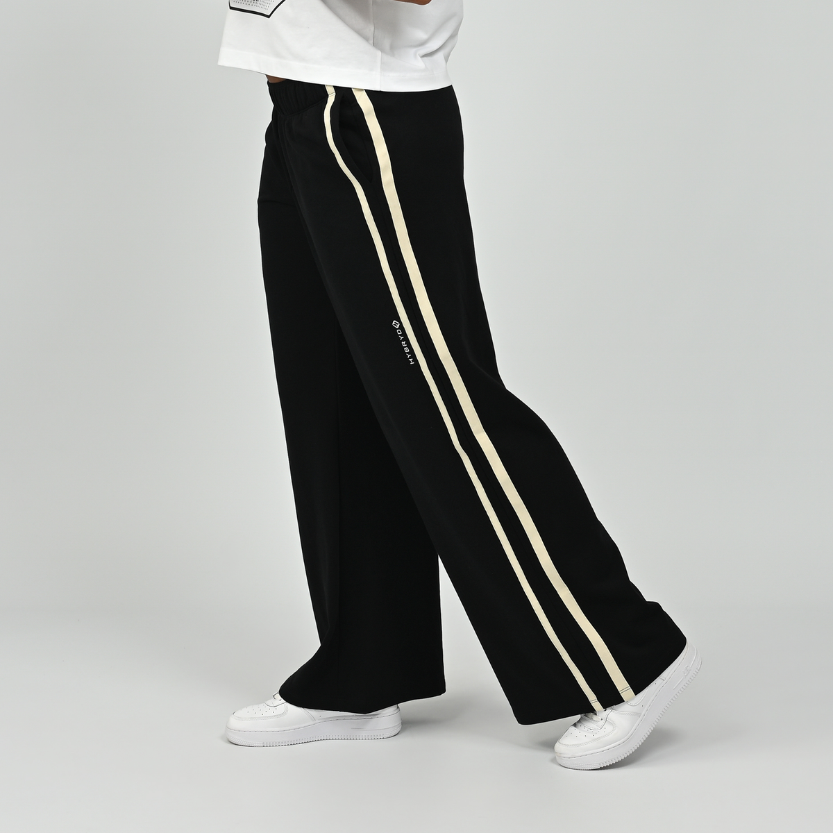 Side profile view of model wearing black Hybryd Milford wide leg joggers showcasing side stripe detai