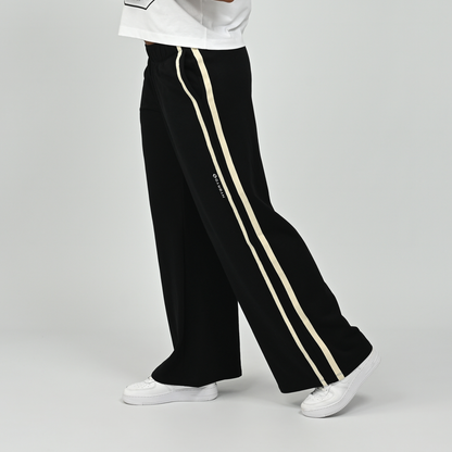 Side profile view of model wearing black Hybryd Milford wide leg joggers showcasing side stripe detai