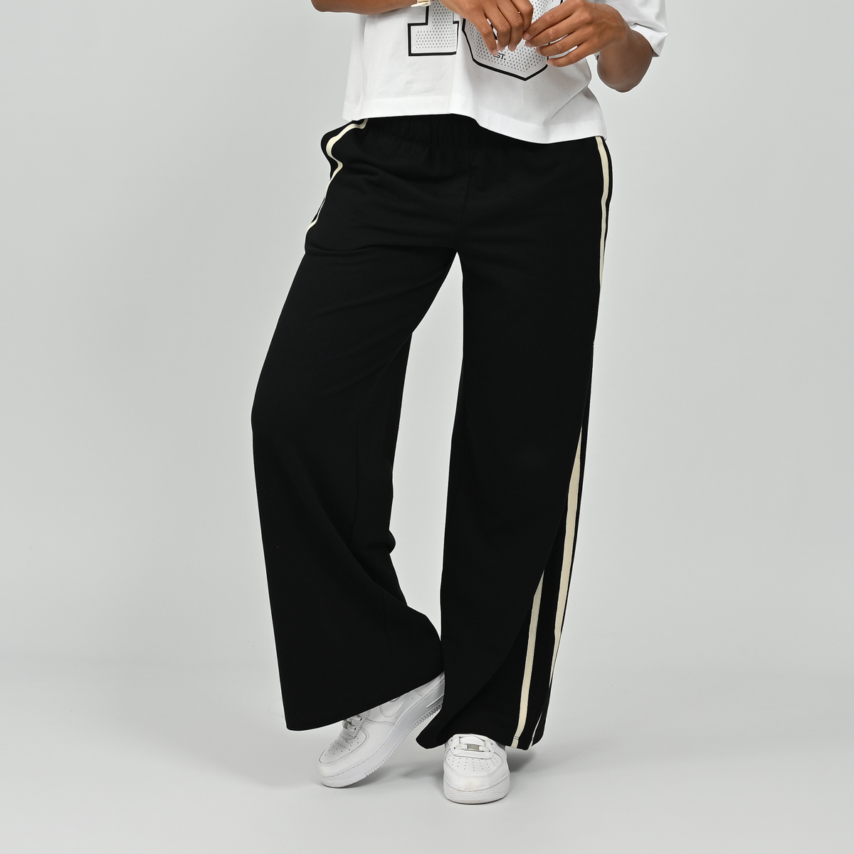 Full length front view of model standing in black Hybryd Milford wide leg joggers   
