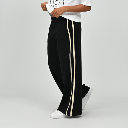 Three-quarter view of model wearing black Hybryd Milford wide leg joggers with side stripe   