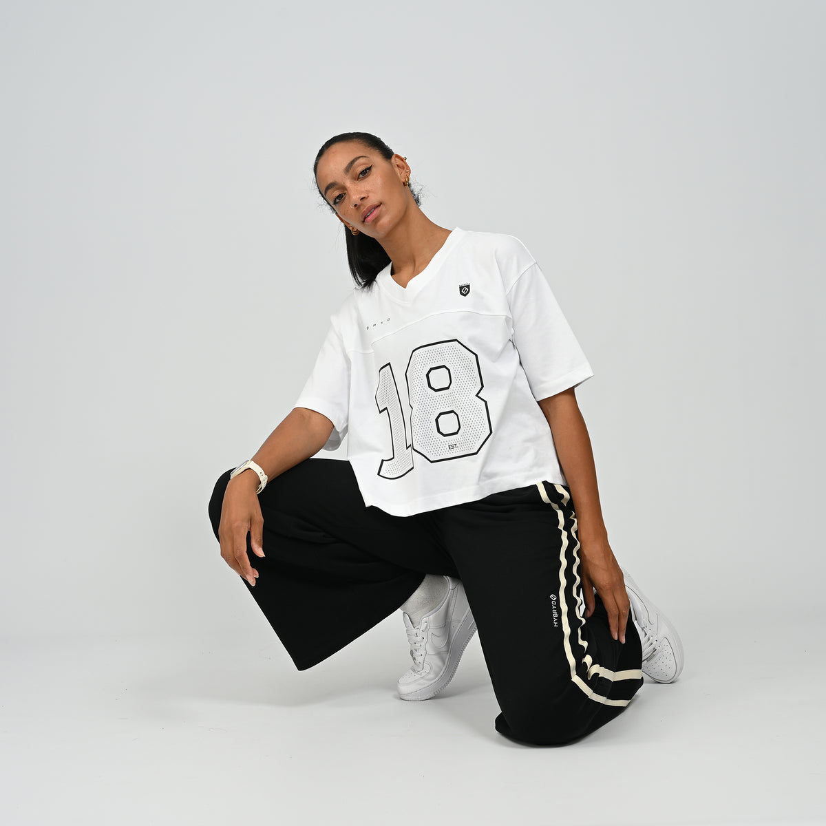 Model sitting on floor wearing black Hybryd Milford wide leg joggers paired with white top   