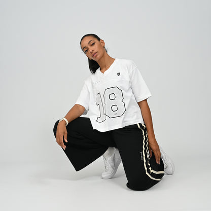 Model sitting on floor wearing black Hybryd Milford wide leg joggers paired with white top   
