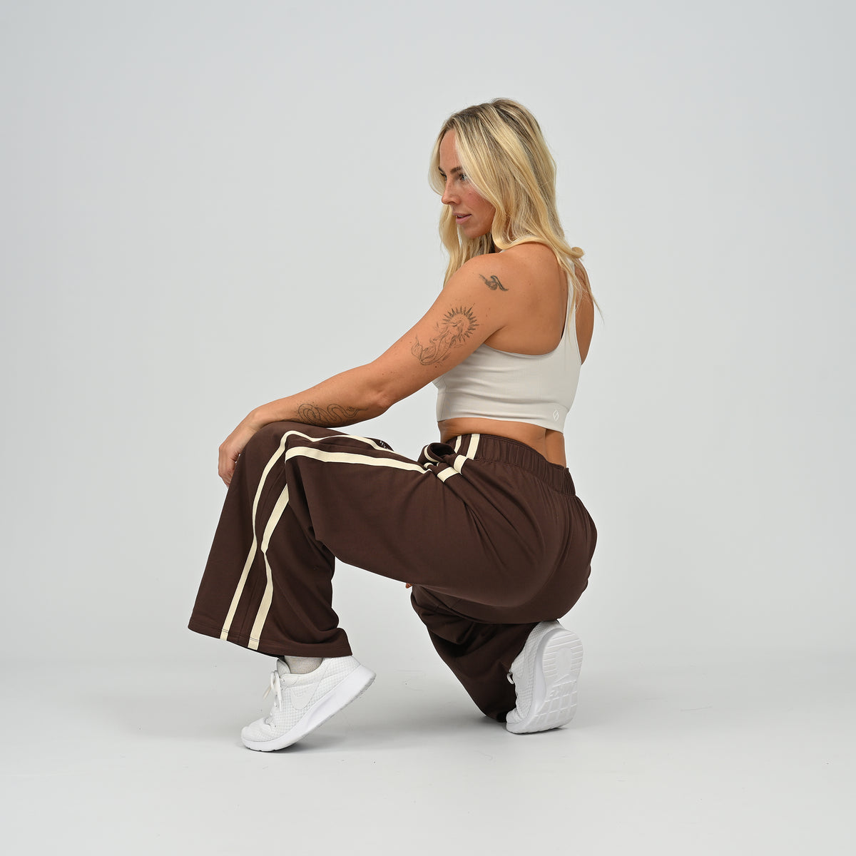 Model crouching pose wearing brown Hybryd Milford wide leg joggers   