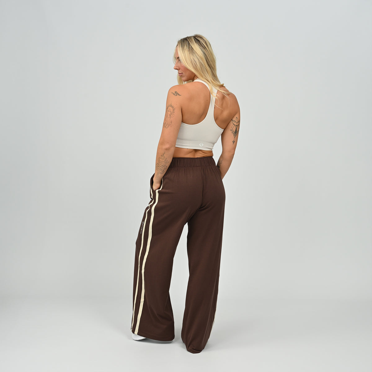 Three-quarter view of model standing in brown Hybryd Milford wide leg joggers   