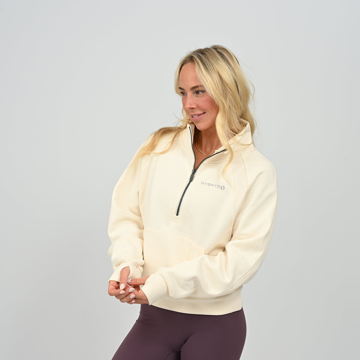 Front posing view of model wearing the cream Hybryd Monterey high collar half zip sweatshirt   