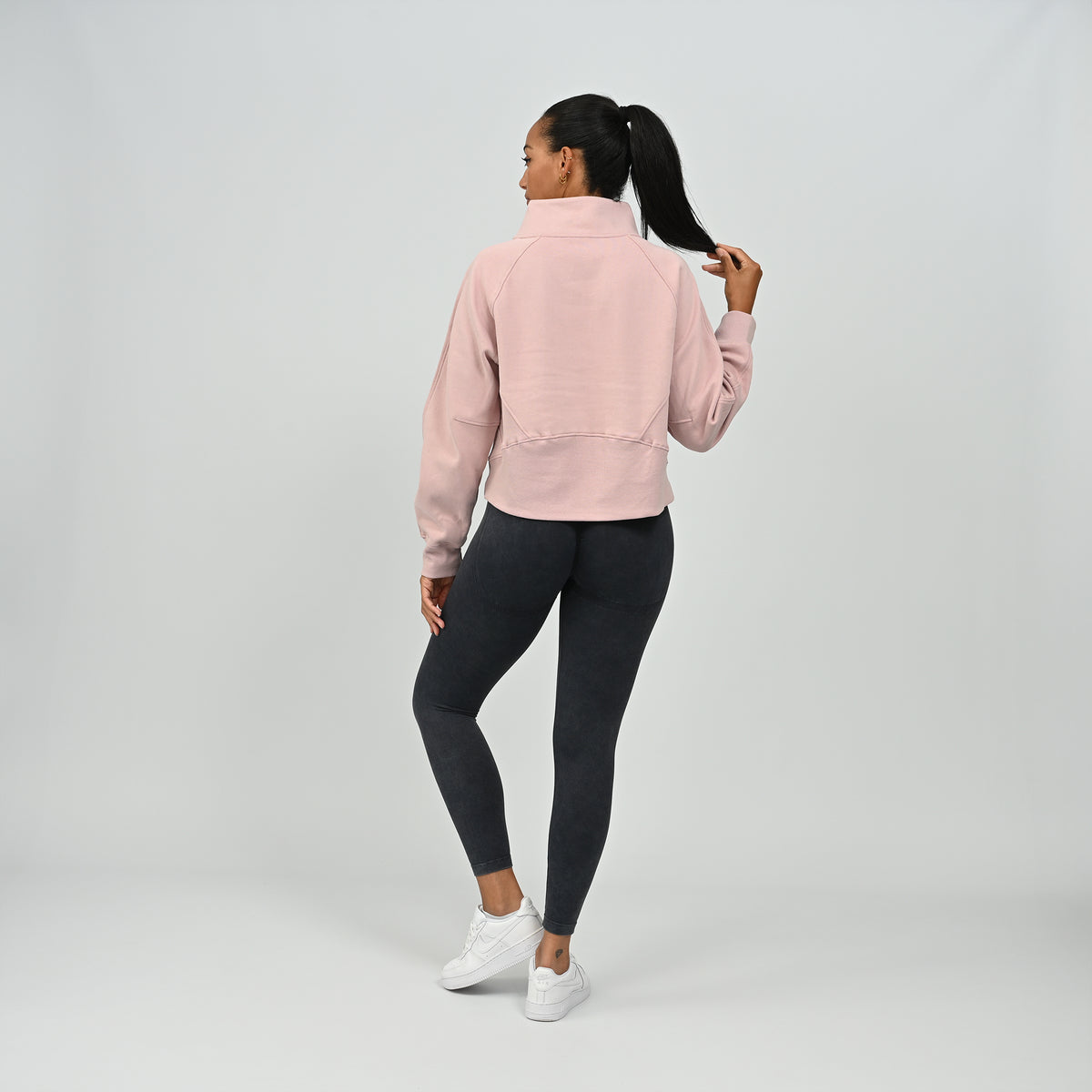 Full length back view of model standing in the dusty pink Hybryd Monterey half zip sweatshirt   